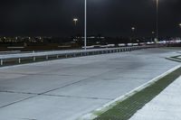 a road with lights on at night as a stop light watches from behind it and a freeway