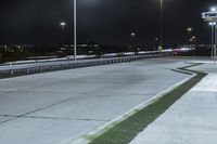 a road with lights on at night as a stop light watches from behind it and a freeway