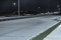 a road with lights on at night as a stop light watches from behind it and a freeway