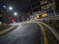 a curved, winding road at night in a city surrounded by tall buildings and a building on the other side