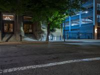 a city street at night with parking meters on either side and the road in the center