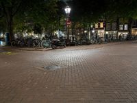 a night view of a street scene with bicycles parked on the pavement and the light in the dark above