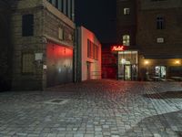 a street scene at night, with the car parked in front of a building and red light lit building