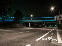 night scene of a street with bridge and light - painted bike lane markings on both sides