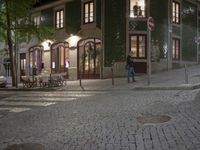 a street scene at night, the sidewalk and the building are all decorated in green