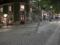 a street scene at night, the sidewalk and the building are all decorated in green