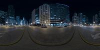 a fish eye view of a street at night with skyscrapers on both sides and a bus driving down one side