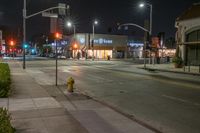 the fire hydrant in front of a store is lit up at night in an empty city