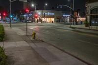 the fire hydrant in front of a store is lit up at night in an empty city