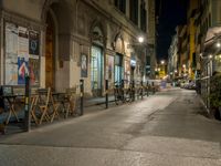 street scene with parked bikes and tables at night time in the city lights are on the windows