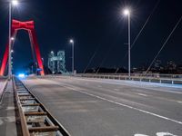 a long bridge with red lights above it at night time, and another bridge over the water behind it