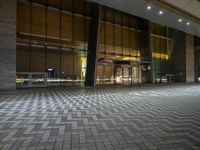 the ground is tiled with stones and glass doors, along with a red light, at night