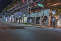 the street light is green at night near the palm trees outside the building and on the sidewalk