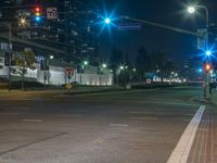 street with no traffic at night next to tall building and traffic lights on street corner