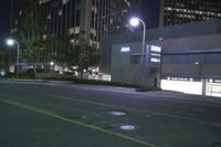 a night scene shows empty road in the distance in front of modern tall buildings in an urban city