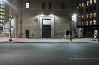 the street that has street lamps, parking meters, and some buildings on it are lit up