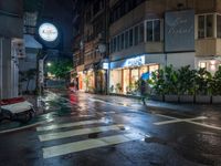 a wet street with a motorcycle parked in front of a large shop at night near street lamps