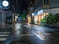 a wet street with a motorcycle parked in front of a large shop at night near street lamps