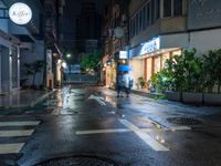 a wet street with a motorcycle parked in front of a large shop at night near street lamps