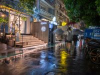 a wet street with a motorcycle parked in front of a large shop at night near street lamps