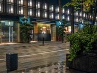 a large brick sidewalk with a store front at night time and a sign that says