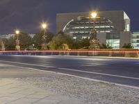 a night shot of a city road with cars passing by and a statue in the background