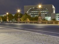 a night shot of a city road with cars passing by and a statue in the background