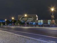 a night shot of a city road with cars passing by and a statue in the background