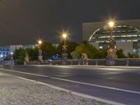 a night shot of a city road with cars passing by and a statue in the background