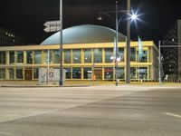 night shot with street lights, large building and road signs at intersection intersection and building