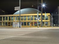night shot with street lights, large building and road signs at intersection intersection and building