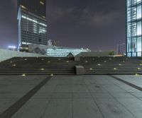 a night shot of an outside stair way in front of a glass office building at the intersection