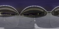 two people on skateboards doing tricks on a curved ramp at night time near a street