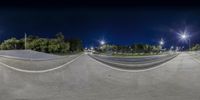 skateboarder doing a trick at night with lights behind him of trees and streetlights