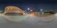 skateboarder rides down a half pipe on a city street at night time,