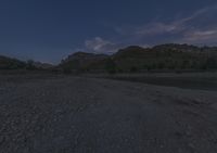 the night sky is reflecting in the river water and rocks on the bank in front of a rocky mountain landscape