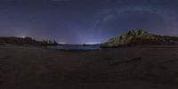 the milky shines brightly in the night sky as seen from a rocky coastline on a dark beach