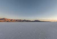 the sky is partly cloudy and clear above the mountains and desert with footprints in the snow