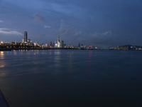 large water area with city lights and skyline in background at dusk time and blue sky