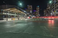 the empty street in front of a terminal with some buildings in the background at night