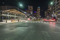 the empty street in front of a terminal with some buildings in the background at night