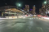 the empty street in front of a terminal with some buildings in the background at night