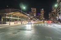 the empty street in front of a terminal with some buildings in the background at night