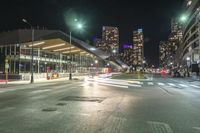 the empty street in front of a terminal with some buildings in the background at night