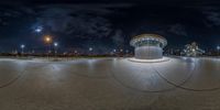 a wide angle view of a very big clock by night with a lot of clouds