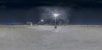 a snow covered field with a snowboard park on it at night in front of a lighted building