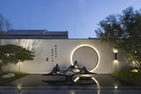 three black and white sculptures in the middle of a stone garden at night next to a white fence with asian writing