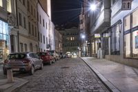 a street at night with cars parked next to it and a sidewalk nearby in the city