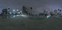 an empty street near buildings at night with a street light and palm trees in the distance