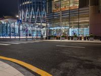 a street that has cars on it and people standing outside at a bus stop in the night